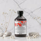 Flacon de 250 ml du Naturaltech Energizing Shampoo de Davines, shampooing anti-chute pour cuir chevelu et cheveux fragiles au Hair Energy Complex et aux phytoceutiques de caféine, posé sur un plan en marbre entouré de galets et de fleurs séchées.