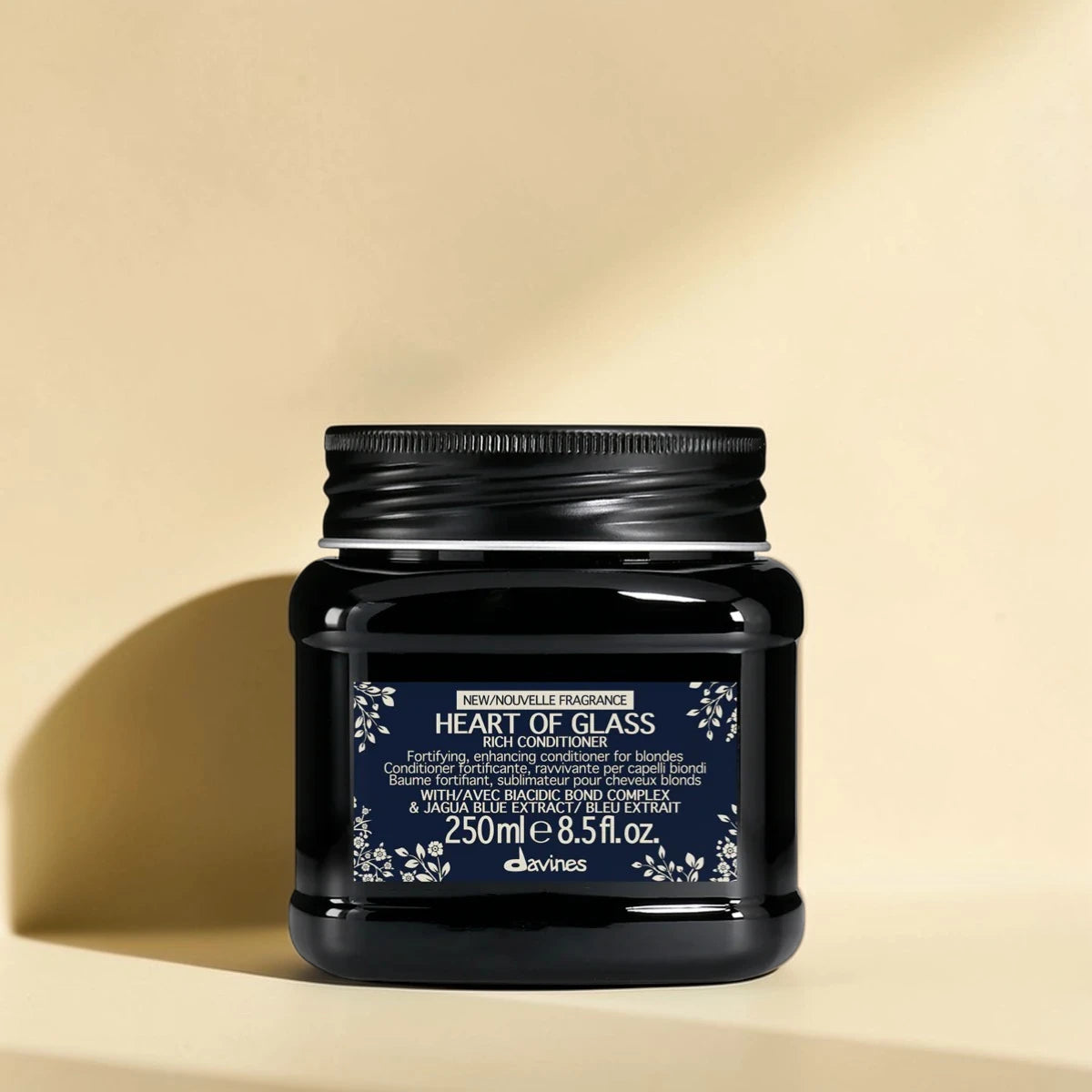 Pot noir de davines Heart of Glass conditionneur sur un fond beige