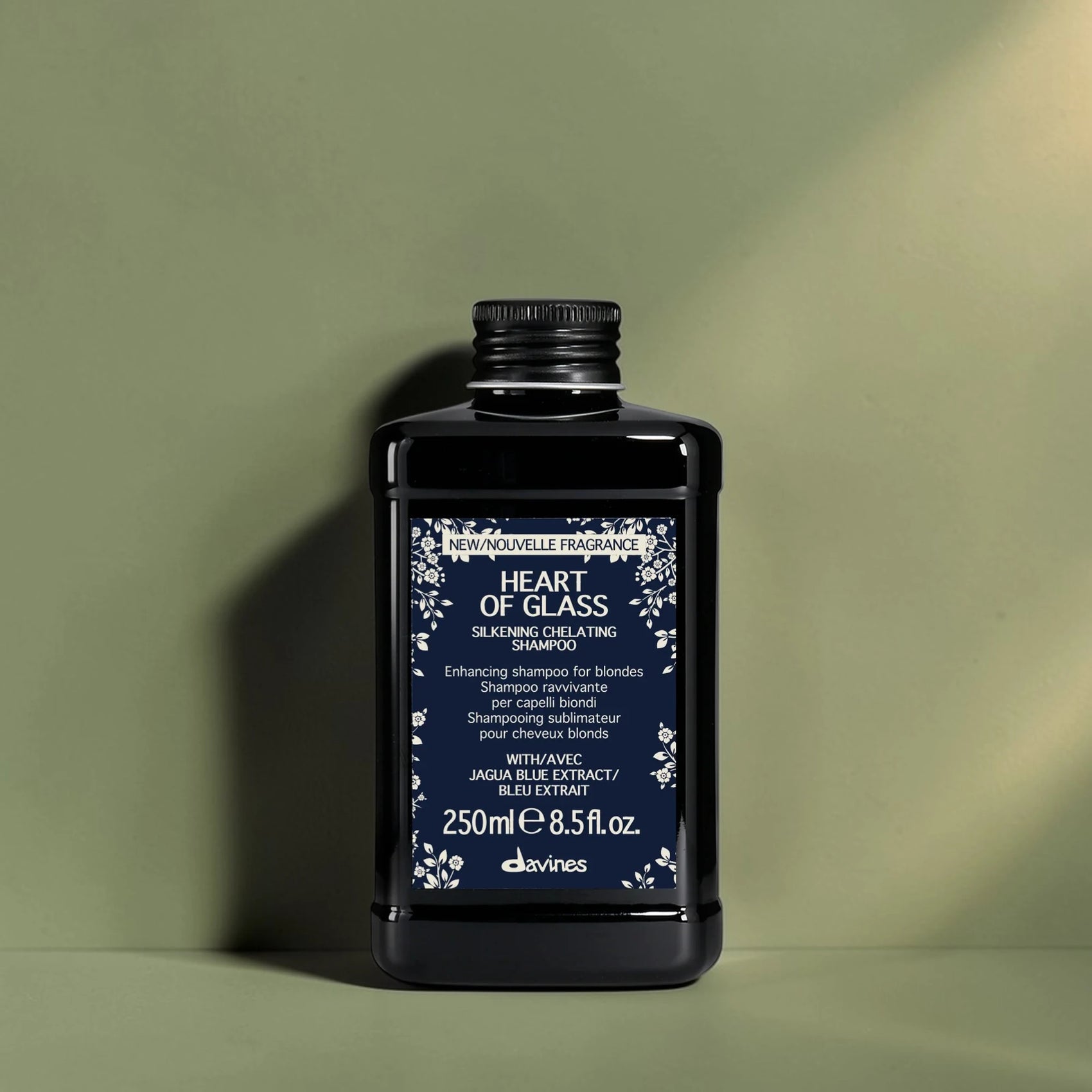 Bouteille de shampooing noir avec étiquette bleue sur un fond vert