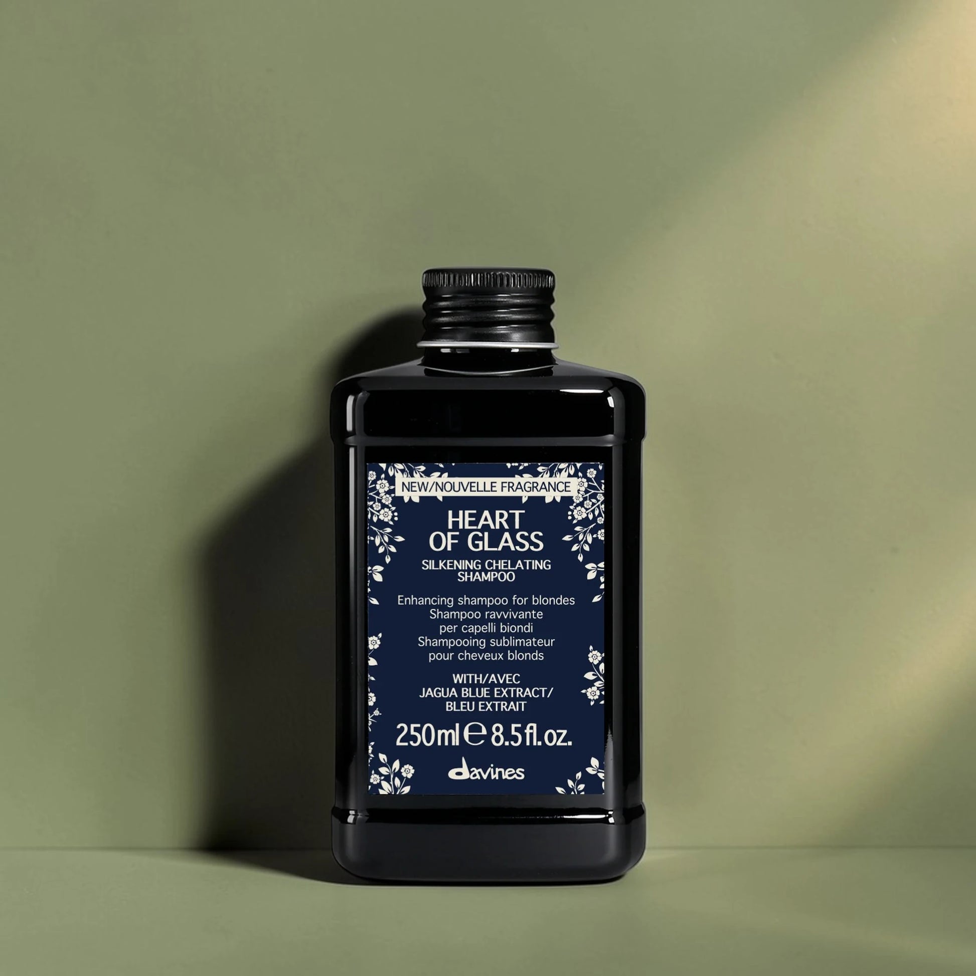 Bouteille de shampooing noir avec étiquette bleue sur un fond vert