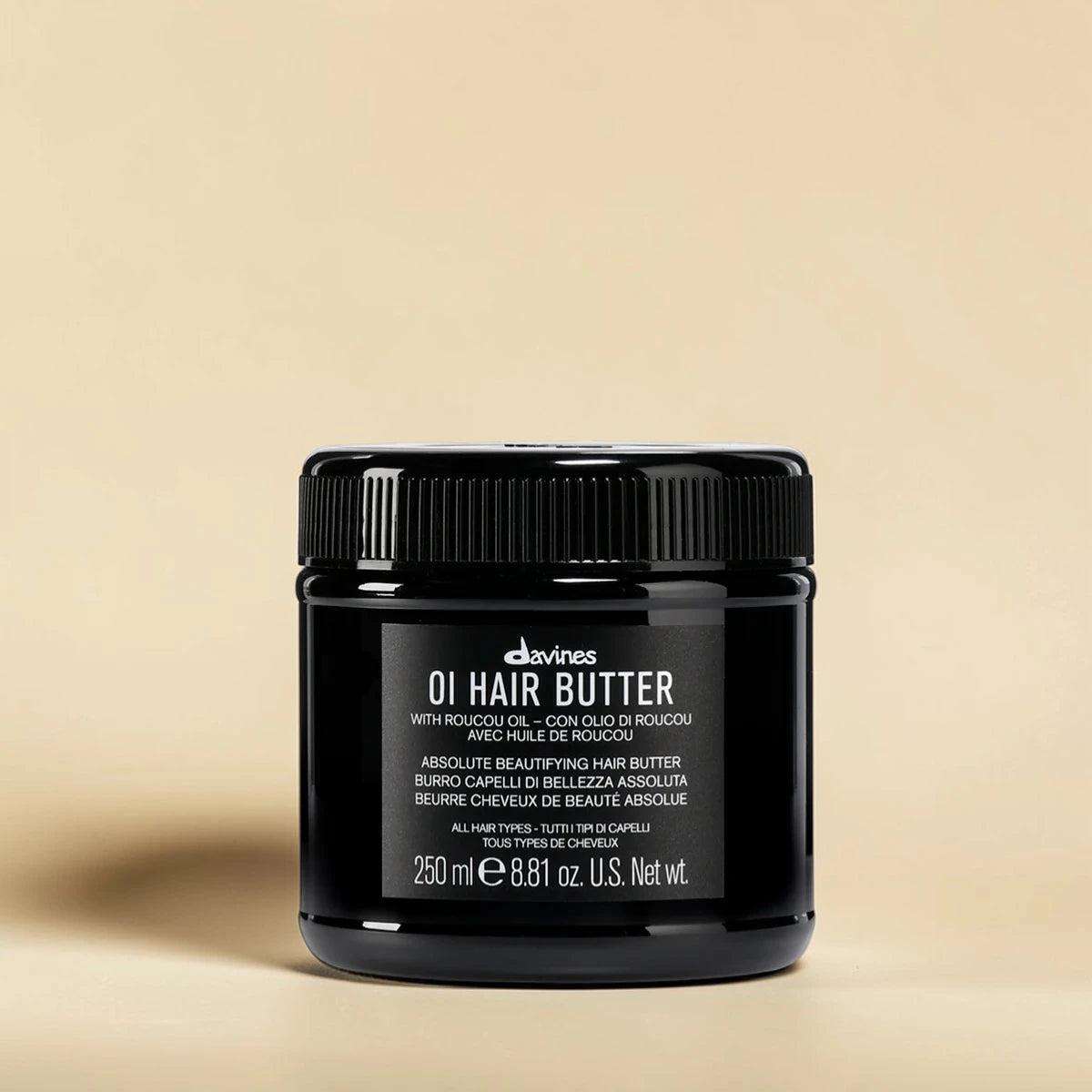Pot noir de Davines OI Hair Butter sur un fond beige