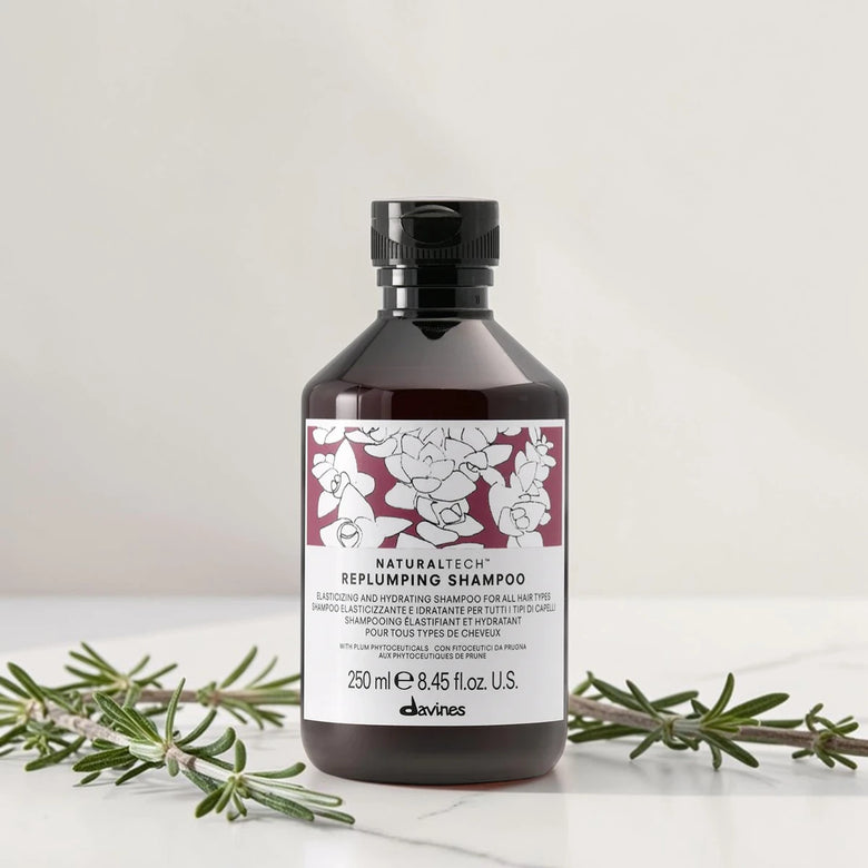 Shampoing Davines Naturaltech Replumping sur marbre blanc avec branches de romarin, Victor Bazin Paris