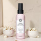 Bouteille de spray thermique crème Maria Nila sur une surface en marbre avec des éléments décoratifs