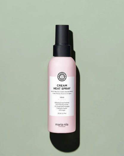 Flacon de spray chauffant crème avec étiquette rose sur fond vert clair