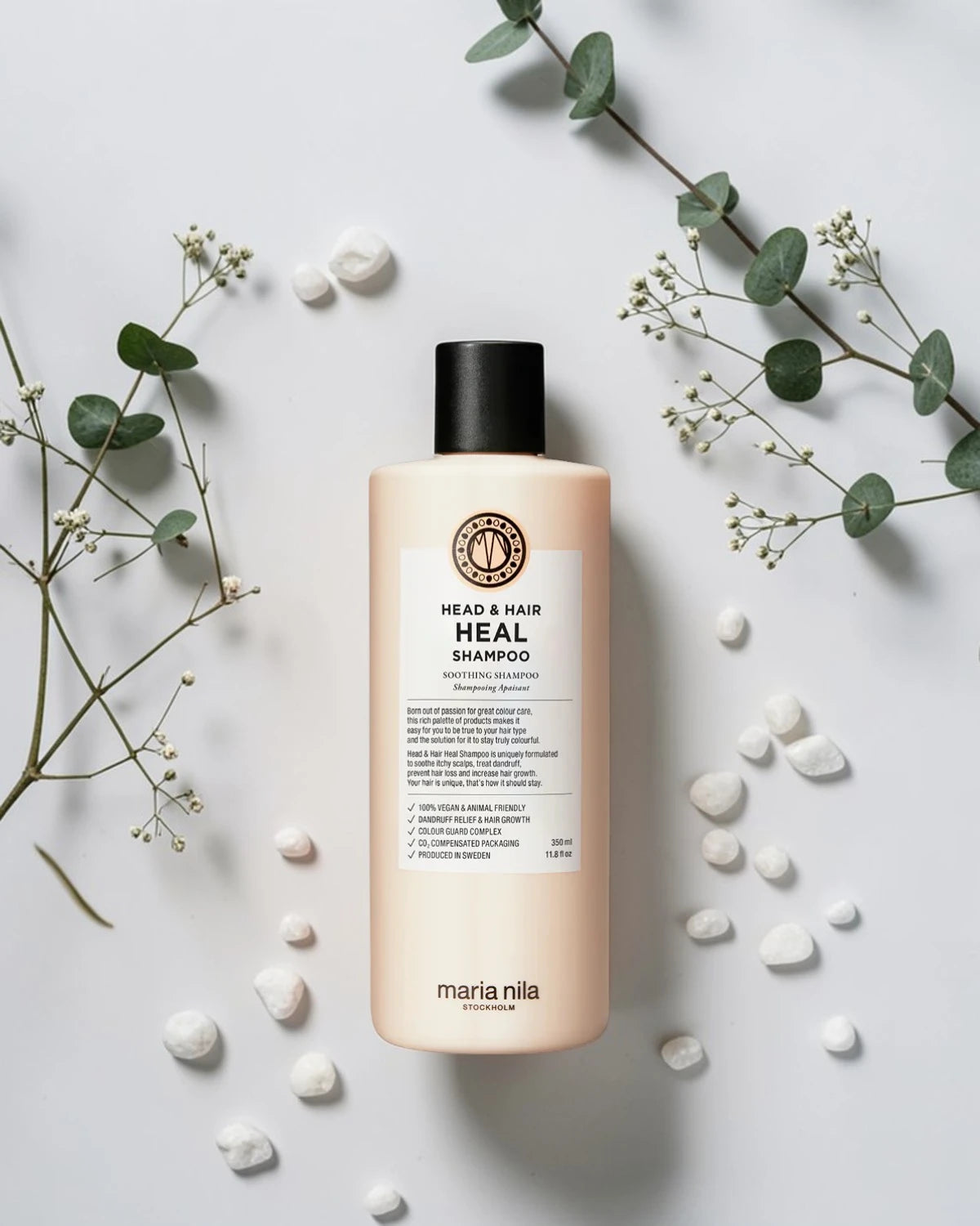 Shampoing Maria Nila Head & Hair Heal sur fond blanc avec eucalyptus et galets blancs, Victor Bazin Paris