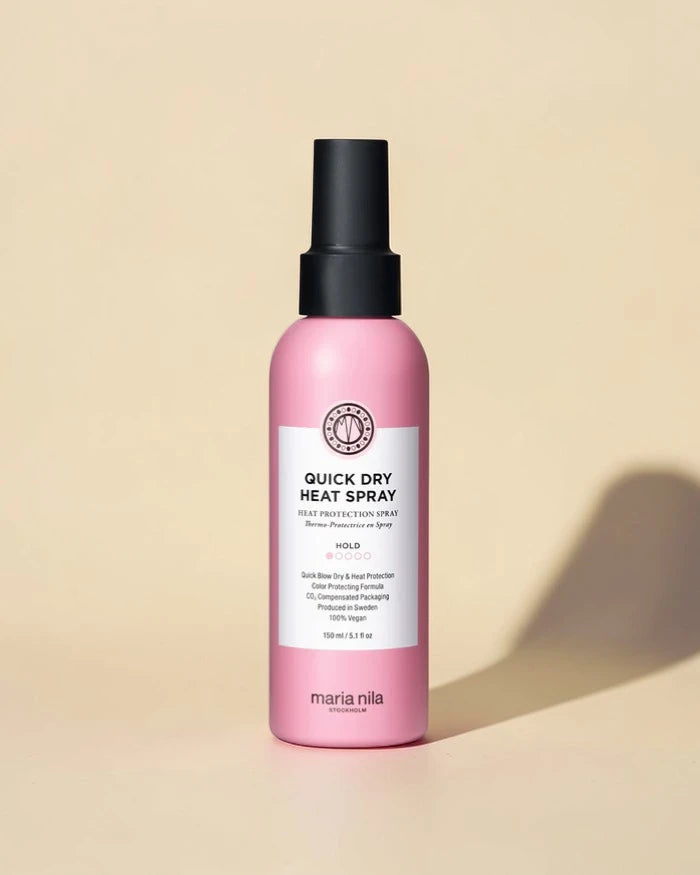 Flacon spray rose de Maria Nila Quick Dry Heat Spray sur un fond beige