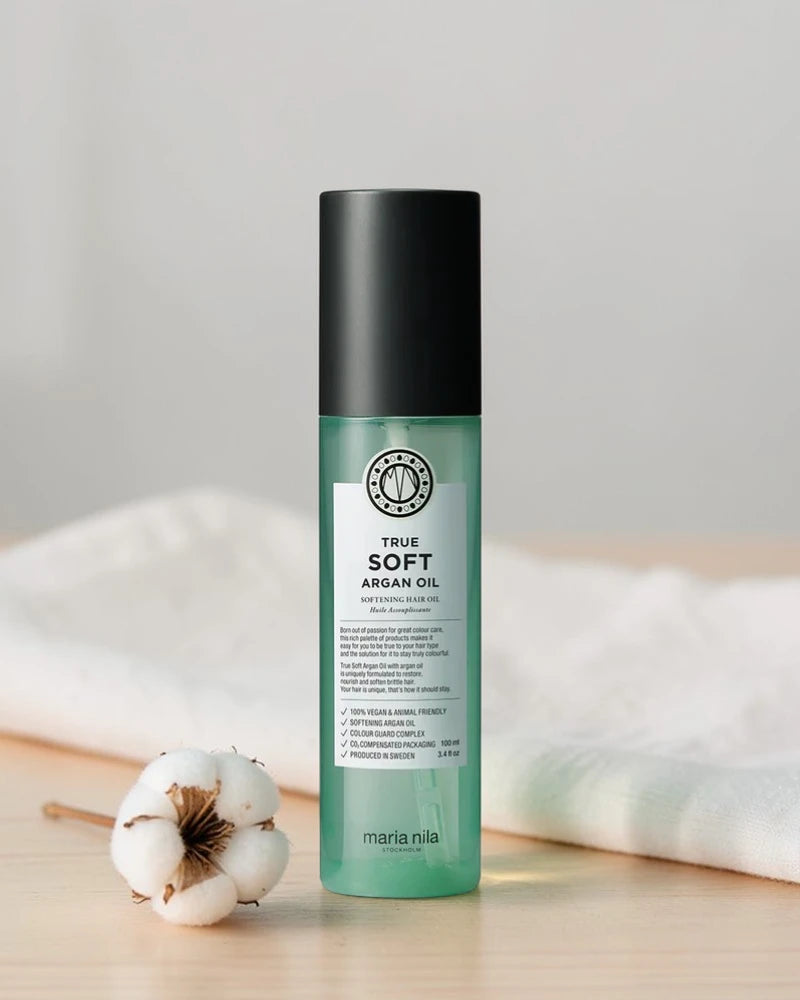 Bouteille d’huile d’argan True Soft de Maria Nila sur une surface en bois avec un fond blanc