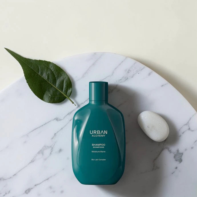 Shampoing Urban Alchemy Moisture Mane sur marbre blanc avec feuille et galet, Victor Bazin Paris