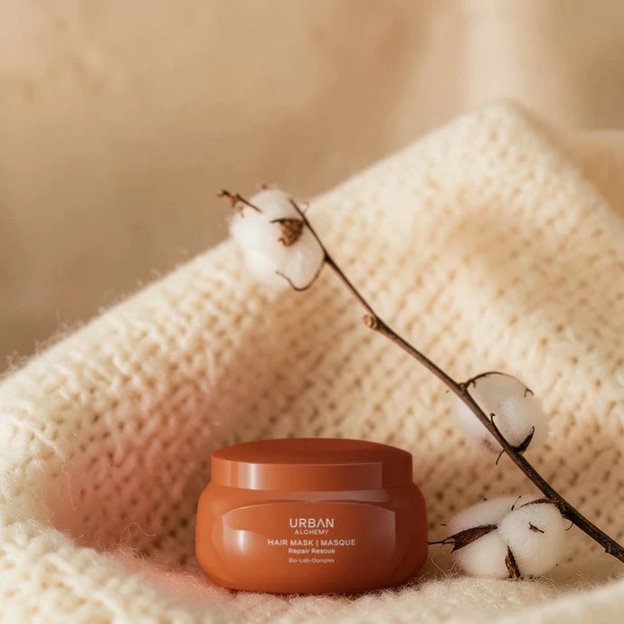 Masque capillaire Urban sur une surface beige texturée avec des branches en coton