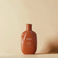 Bouteille de shampooing marron étiquetée "Urban Alchemy" sur fond beige