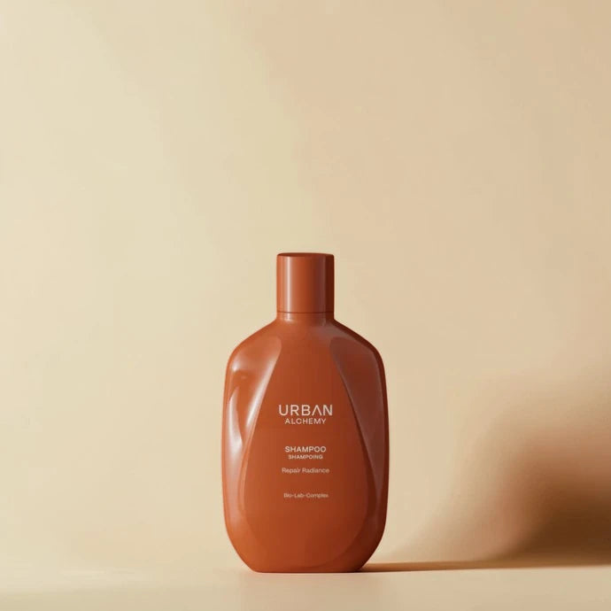 Bouteille de shampooing marron étiquetée "Urban Alchemy" sur fond beige