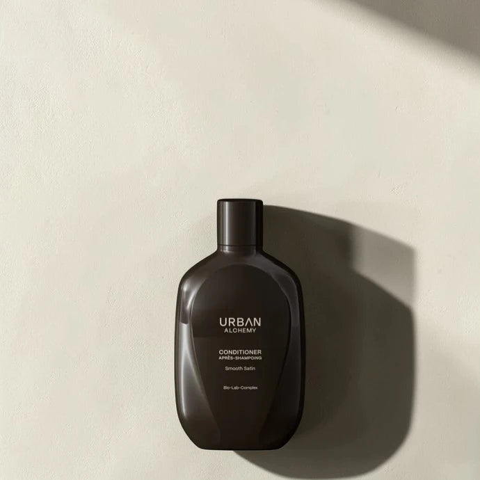 Après-shampoing Urban Alchemy Smooth Satin sur fond crème, lumière naturelle douce, Victor Bazin Paris