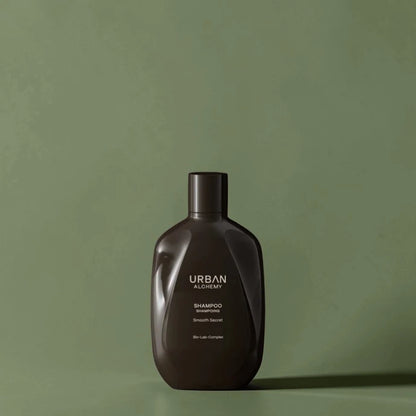 Flacon de shampoing marron foncé étiqueté "Urban Alchemy" sur fond vert