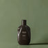 Flacon de shampoing marron foncé étiqueté "Urban Alchemy" sur fond vert