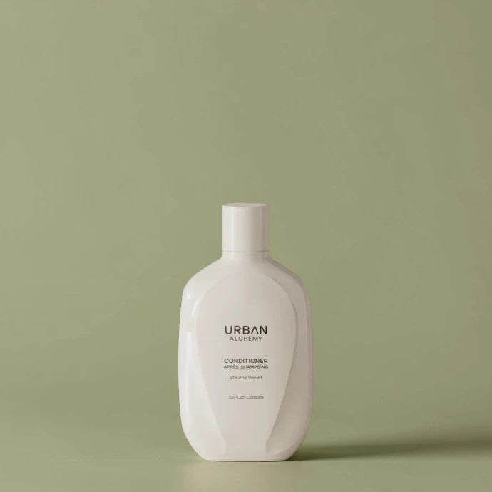 Bouteille blanche d’après-shampoing Urban Alchemy sur fond vert