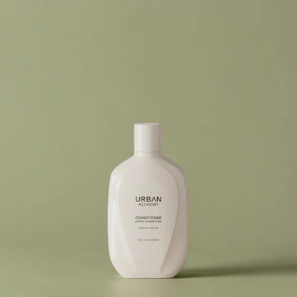 Bouteille blanche d’après-shampoing Urban Alchemy sur fond vert