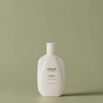 Flacon de shampooing blanc étiqueté "Urban Alchemy" sur fond vert clair